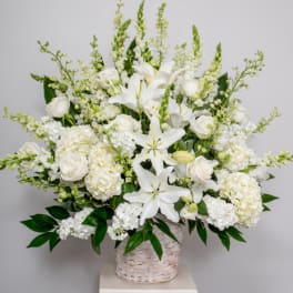 White lilies and roses in a woven basket arrangement