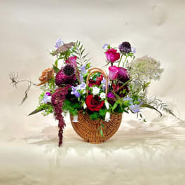 Mixed flower arrangement in a wicker basket with red and pink roses