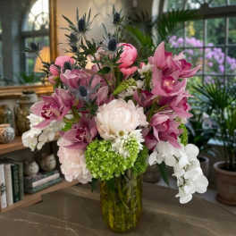 Pink and white orchid arrangement in a glass vase with green hydrangea