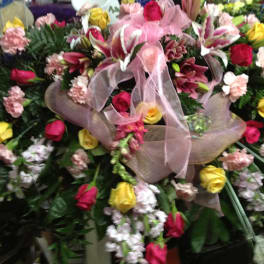 Large mixed floral arrangement with roses, lilies, and carnations in pink, yellow, and red