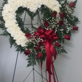 Heart-shaped white floral wreath with red roses and a red ribbon