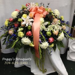 Large floral spray with a peach ribbon and mixed blooms in white, pink, yellow, and blue