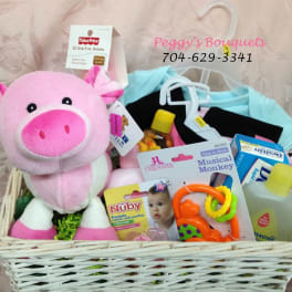 Gift basket with a pink plush pig, baby clothes, pacifier, and baby care items