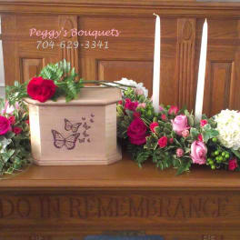 Casket spray with pink and white roses around a butterfly urn