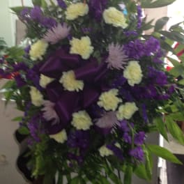 Purple and cream floral standing spray with dark ribbon accents
