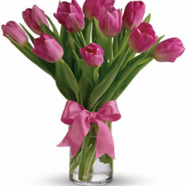Pink tulips in a clear glass vase with a pink ribbon