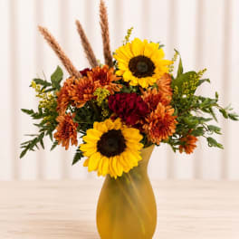 Sunflowers and orange chrysanthemums in a yellow vase