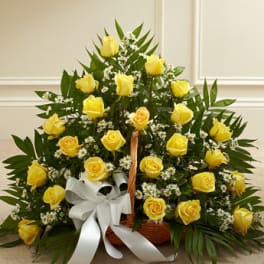 Basket of yellow roses with small white filler flowers and a white ribbon