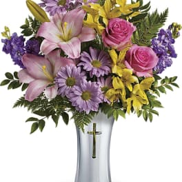 Pink lilies, roses, and purple daisies arranged in a silver vase