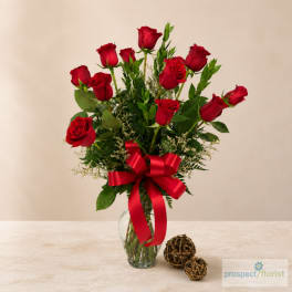 Red roses arranged in a clear glass vase with a red ribbon
