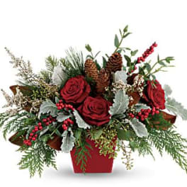 Red roses in a red container with pinecones and winter greenery
