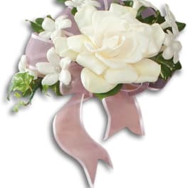 White rose corsage with small white flowers and pink ribbon