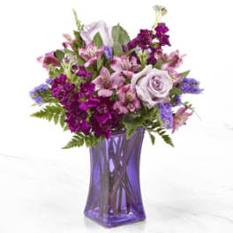 Purple and pink mixed bouquet in a tall purple glass vase