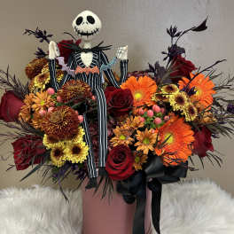 Halloween bouquet with roses, gerbera daisies, and a Jack Skellington figure in a pink box