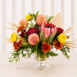Colorful mixed bouquet in a clear glass pedestal vase