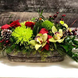 Low floral centerpiece with red roses, green mums, and orchids in a rustic container