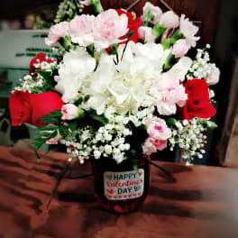 Bouquet of red roses, pink carnations, and white hydrangea in a vase