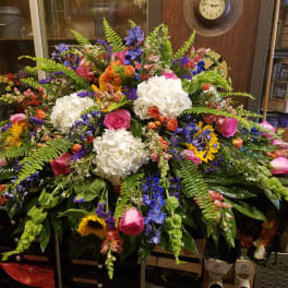 Large mixed floral arrangement with white hydrangeas, pink roses, and blue flowers