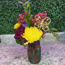 Colorful bouquet in a green glass vase with a decorative bow