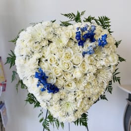 Heart-shaped white floral standing arrangement with blue accents