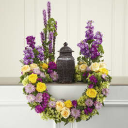 Floral wreath with yellow and lavender roses around a dark urn