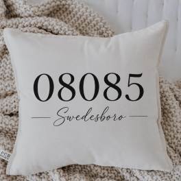 White decorative pillow with black text on a knitted throw