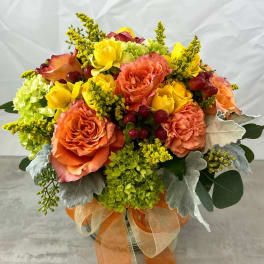 Orange and yellow rose bouquet in a glass vase with ribbon