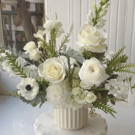 White floral arrangement in a ribbed cream vase