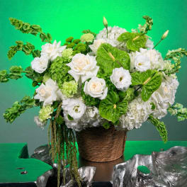 White and green floral arrangement in a woven basket