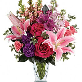 Pink lilies and roses arranged in a clear glass vase