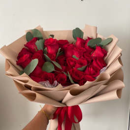 Bouquet of red roses wrapped in beige paper with a red ribbon