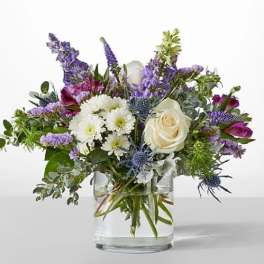 Mixed bouquet of white and purple flowers in a clear glass vase