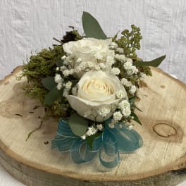 White roses with baby's breath and moss on a wood slice