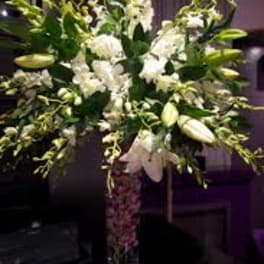 Tall white lily arrangement in a patterned glass vase