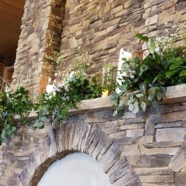 Greenery and white floral garlands arranged on a stone mantel with candles