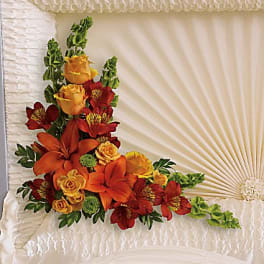 Floral spray on a white casket with red and orange flowers