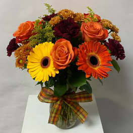 Bouquet of orange roses, gerbera daisies, and mums in a glass vase