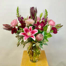 Mixed pink and burgundy flowers in a clear glass vase