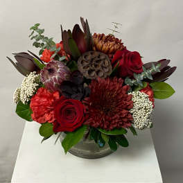Red and burgundy floral arrangement in a clear glass vase