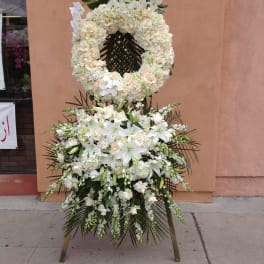 White floral funeral wreath and standing spray on an easel