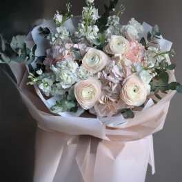 Pastel bouquet of white and blush flowers wrapped in pale pink paper