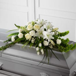 White floral arrangement on a gray casket