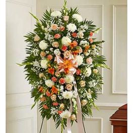 Standing funeral spray with white, peach, and orange flowers on a ribboned easel
