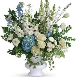 White and blue floral arrangement in a white pedestal vase