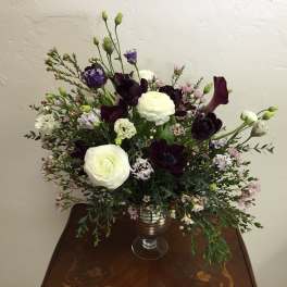 White and dark purple floral arrangement in a glass vase