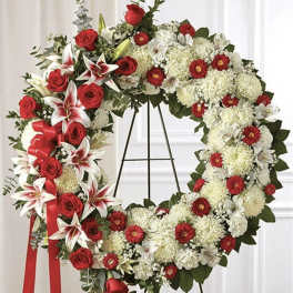Heart-shaped floral wreath with red roses and white flowers on a stand