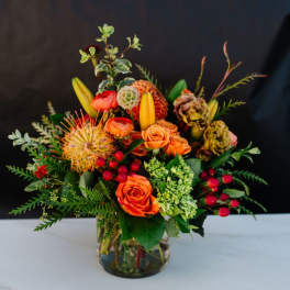 Orange roses and mixed blooms arranged in a glass vase