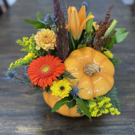Fall floral arrangement with orange pumpkin decor and mixed blooms