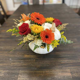 Pumpkin-shaped floral arrangement with orange gerberas, red roses, and yellow blooms