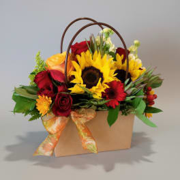 Mixed bouquet with sunflowers, red roses, and a ribboned gift box